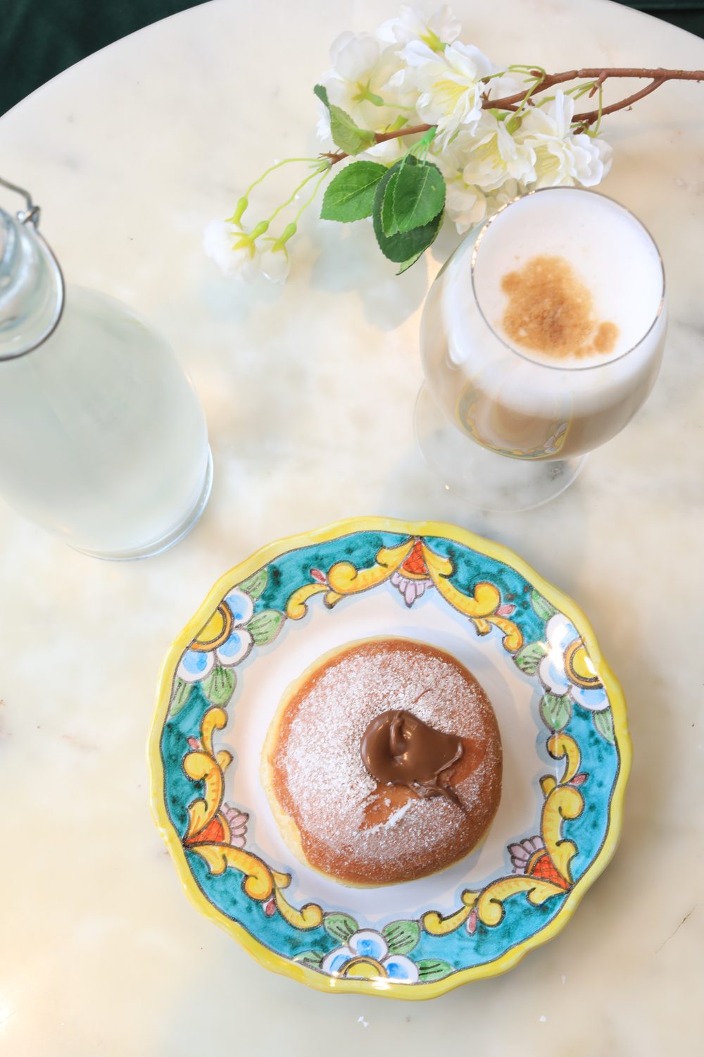 Bombolone and cappuccino on a hand-painted ceramic plate